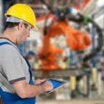 Factory worker using tablet to operate a robotic arm