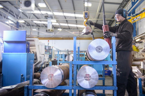 Employee using crane to lift steel in factory