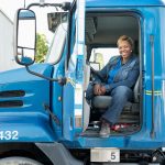 Smiling Black woman sitting in semi-truck