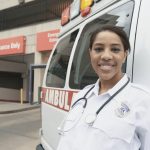 African female EMT next to ambulance